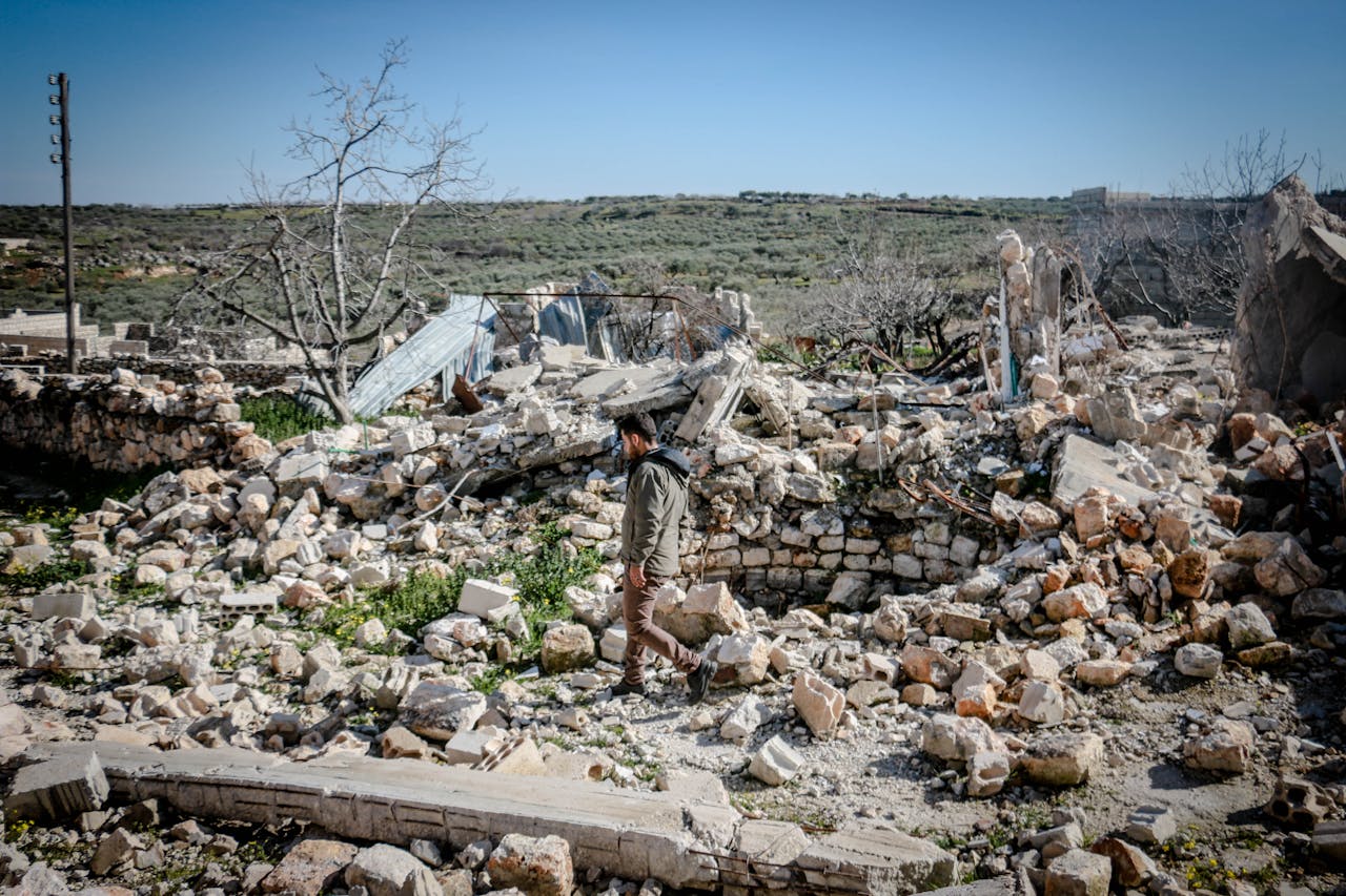 A man navigates through rubble after an earthquake in rural Idlib, Syria.